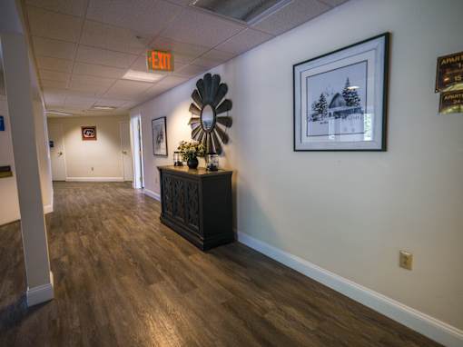 A hallway with a wooden floor and a decorative fan on a table.