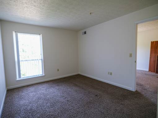 A room with a window and carpeted floor.