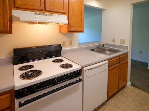 A kitchen with a white stove top oven and a white dishwasher.