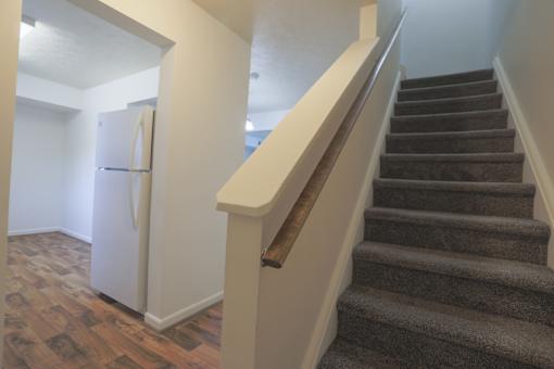 A staircase with a carpeted runner and wooden handrail.