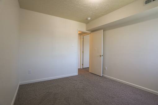A room with a carpeted floor and a doorway leading to another room.