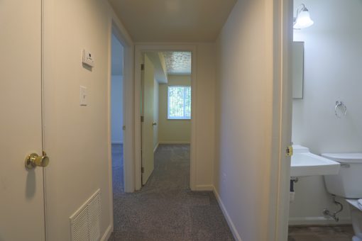 A hallway with a white door and a white sink.