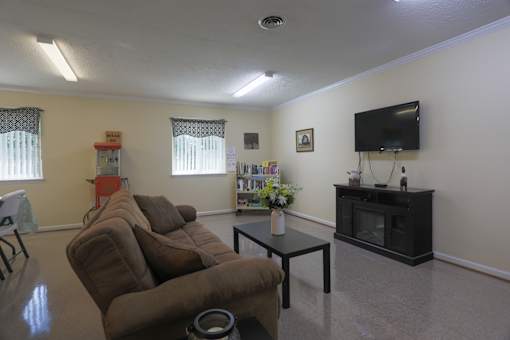 A living room with a brown couch, a black coffee table, and a flat screen TV mounted on the wall.