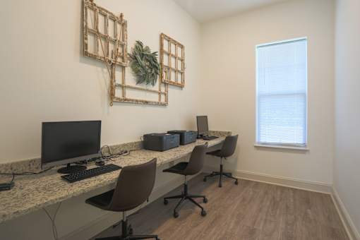 A room with a desk, chairs, and a plant.