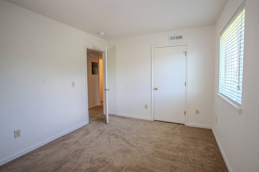 A room with a carpeted floor and two doors.