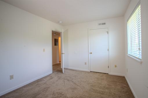 A room with a carpeted floor and two doors.
