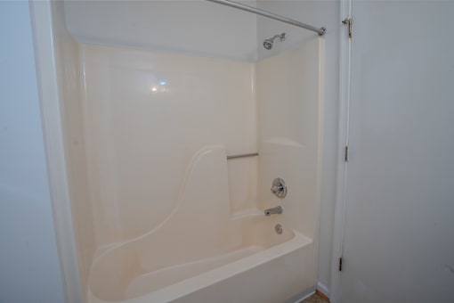 A white bathtub with a shower head and faucet.