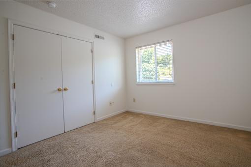 A room with a white door and a window with blinds.