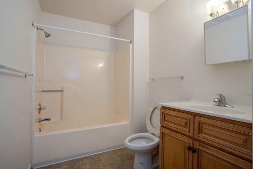 A white toilet sits in a bathroom next to a bathtub.