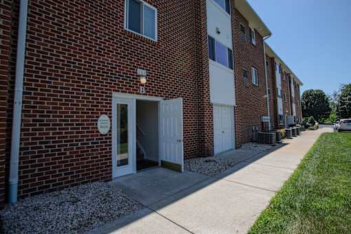 A brick building with a white door and a sign on the ground.