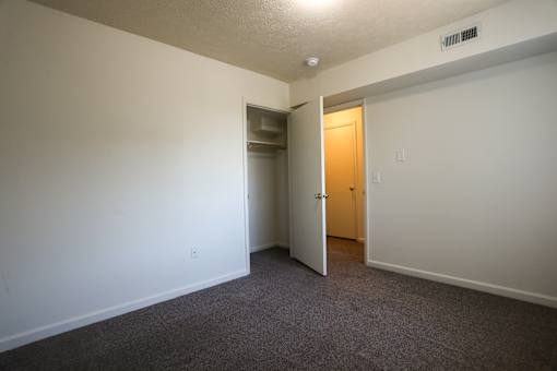 A room with a carpeted floor and a doorway leading to another room.