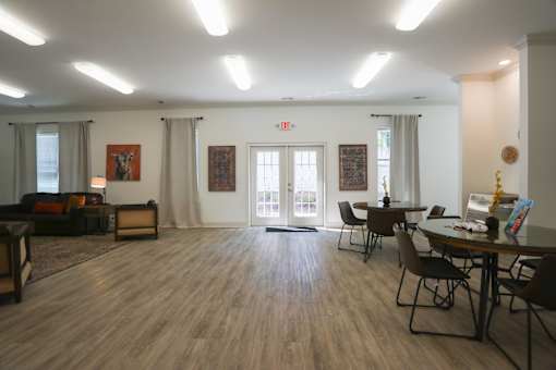 A room with a wooden floor and a white wall with a painting on it.