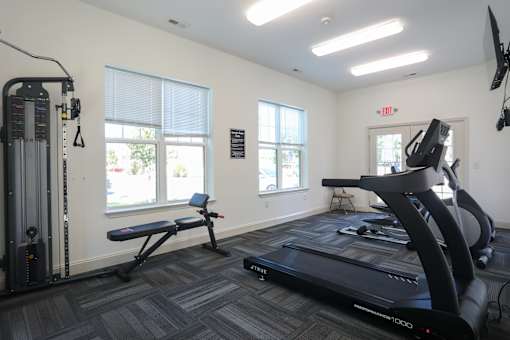 A gym with a treadmill, a bench, and a television.