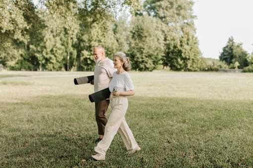 A man and a woman are walking in a grassy field.