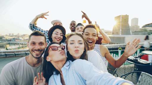 A group of friends are taking a selfie on a rooftop.