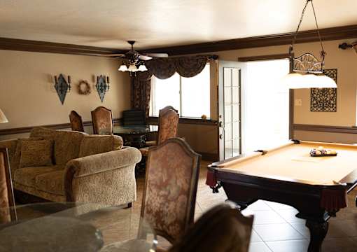 A pool table is in the middle of a room with a couch and chairs.