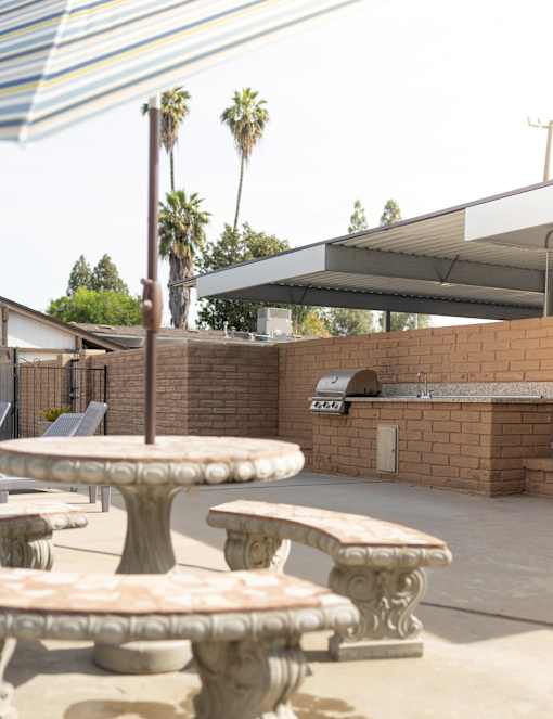 A patio with a table and chairs and a brick wall.