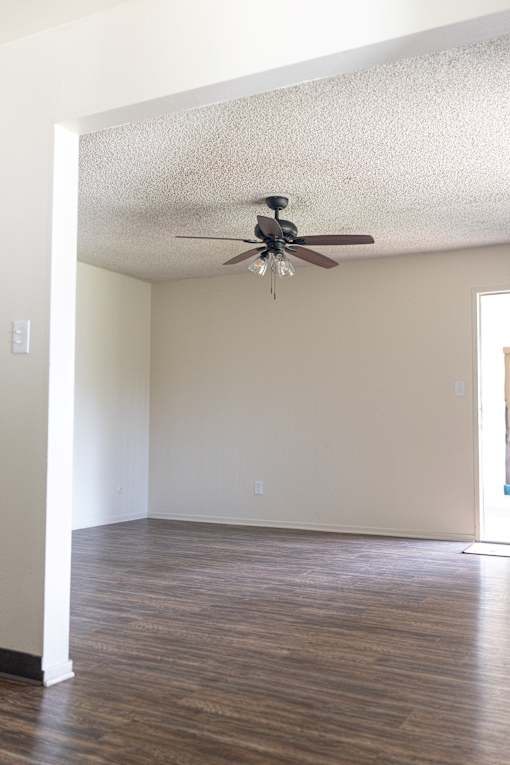 A room with a ceiling fan and wooden floors.