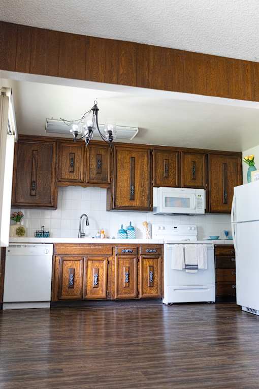 A kitchen with white appliances and wooden cabinets.