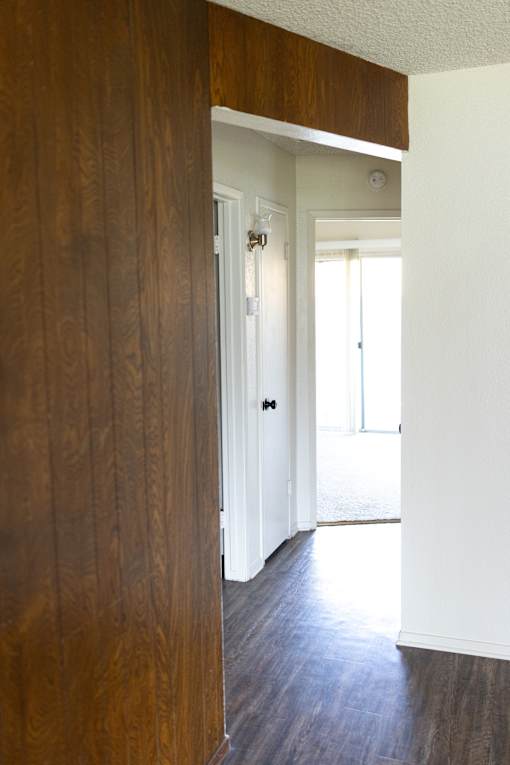 A hallway with a white door and a brown wood panelled wall.