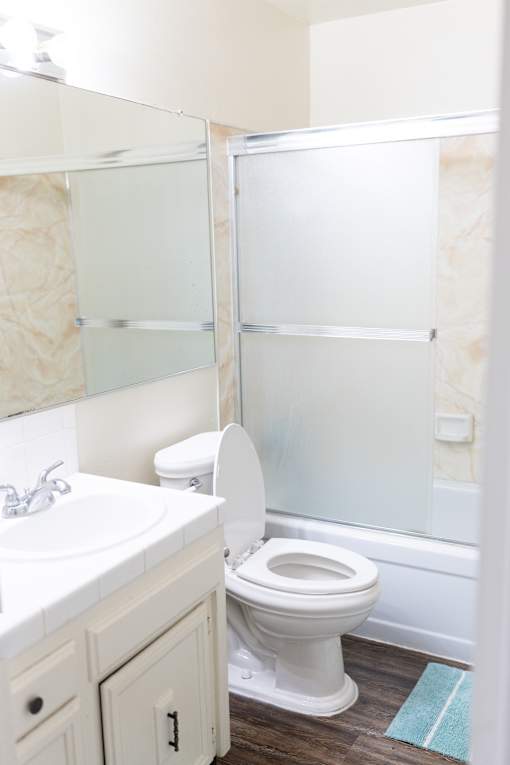 A white toilet in a bathroom with a white sink and a mirror.