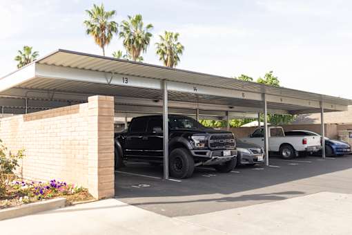 A black truck is parked under a shelter with the number 13 on it.