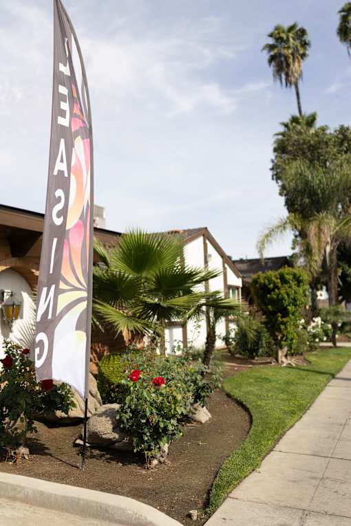 A sign with the word "Avenue" on it is in front of a house with a landscaped yard.