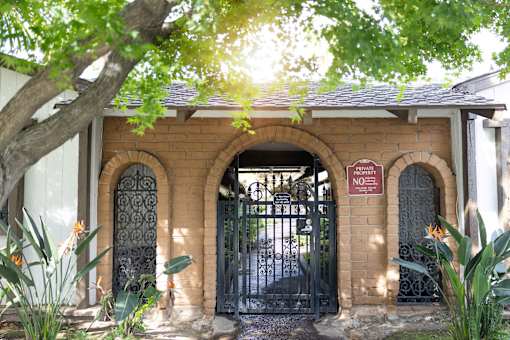 A black gate with a sign that says "No Parking" is in front of a brick building.