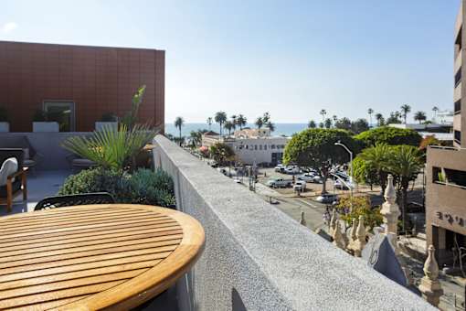 A patio with a table and chairs overlooks a street.