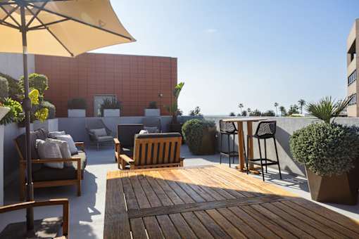 A patio with a table, chairs, and a yellow umbrella.