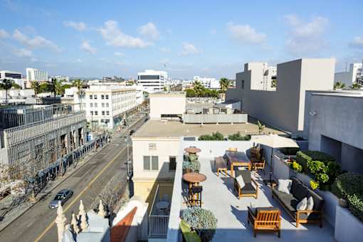 A rooftop patio with chairs and tables overlooks a city street.