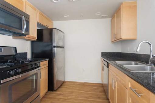 A kitchen with black appliances and wooden cabinets.