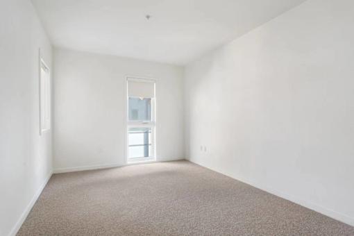 A room with a carpeted floor and a window.