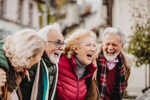 A group of elderly people are laughing together in a park.