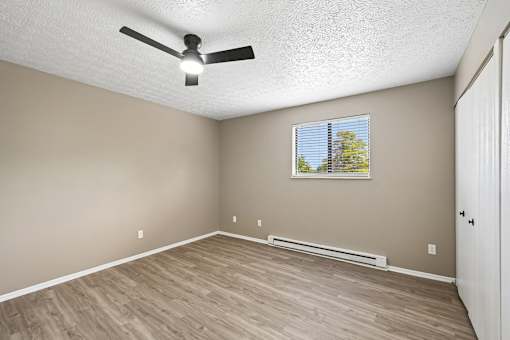 A room with a ceiling fan and a window with blinds.