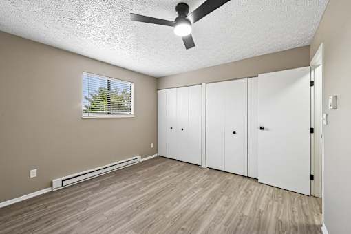 A room with a ceiling fan and a window with blinds.