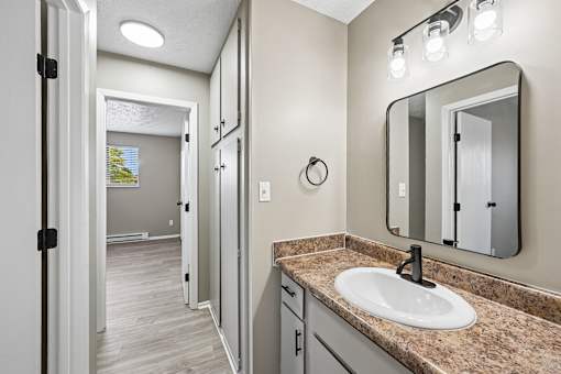 A bathroom with a sink, mirror, and lights.