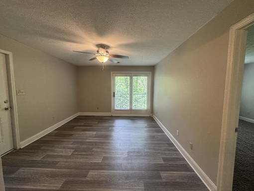 A room with a ceiling fan and a sliding glass door.