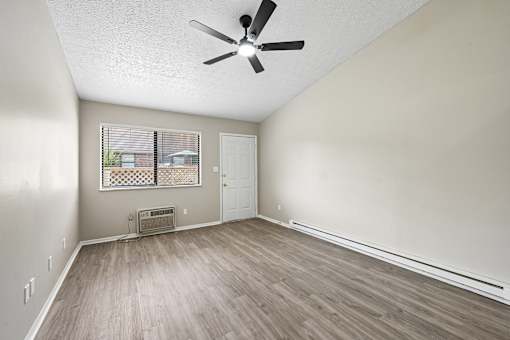 A room with a ceiling fan and a window with blinds.