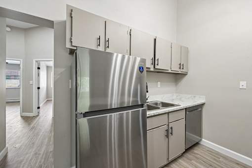 A kitchen with a stainless steel refrigerator and white cabinets.