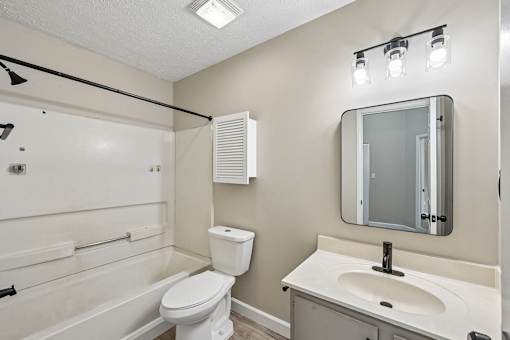 A white bathroom with a toilet, sink, and mirror.