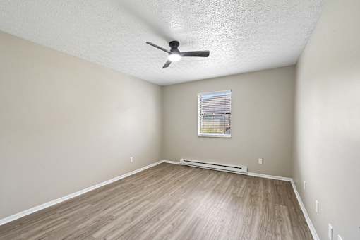A room with a ceiling fan and a window with blinds.