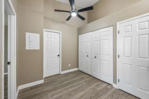 A room with a ceiling fan and three doors.
