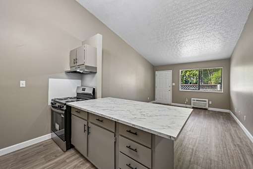 A kitchen with a white countertop and wooden flooring.