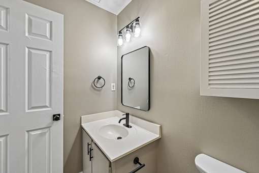 A white sink in a bathroom with a mirror above it.