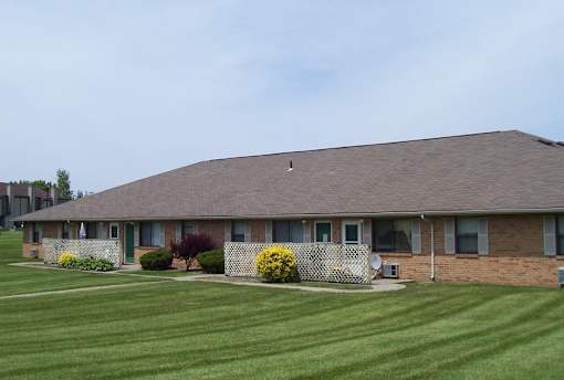 A house with a brown roof and a green lawn in front.