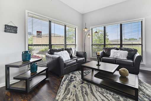 A living room with black leather couches and a coffee table with a vase and a baseball on it.