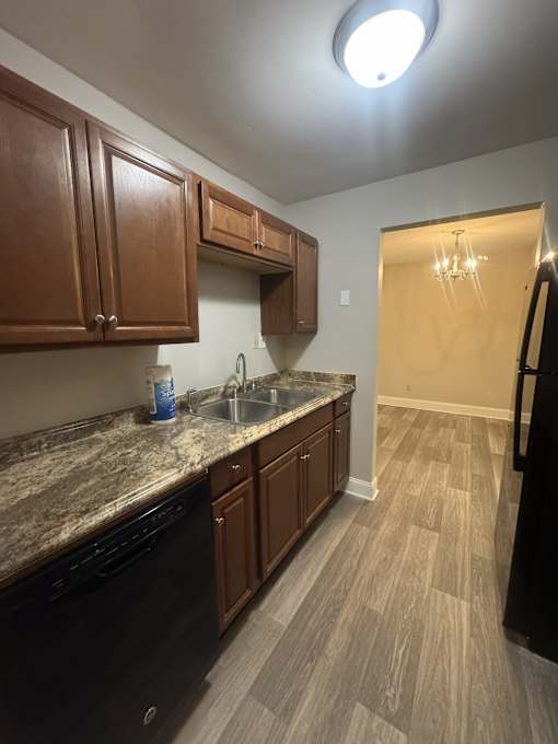 A kitchen with brown cabinets and a black dishwasher.