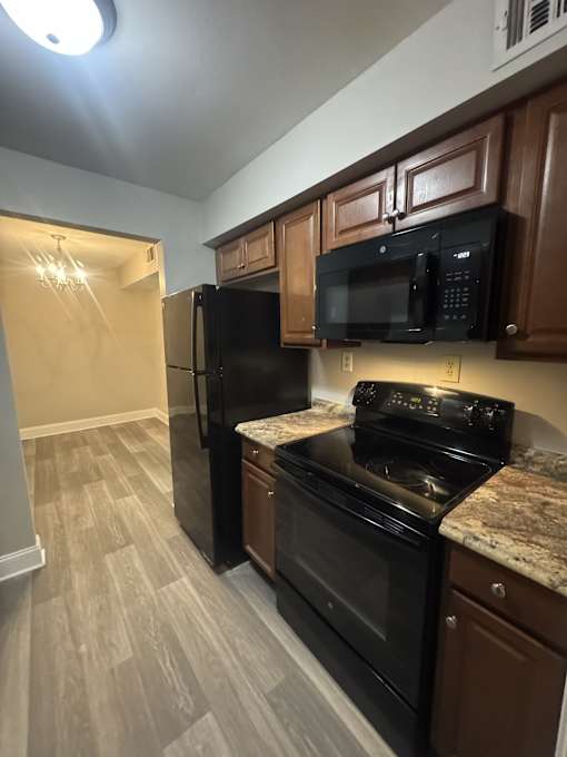 A kitchen with black appliances and wooden cabinets.