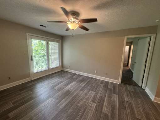 A room with a ceiling fan and sliding glass doors.